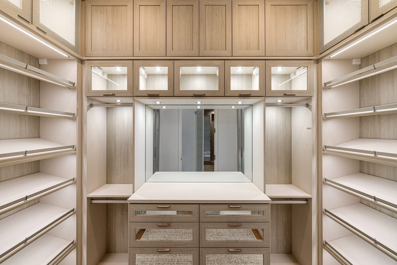 heros-img Spacious walk-in closet with wooden cabinets and ample lighting.